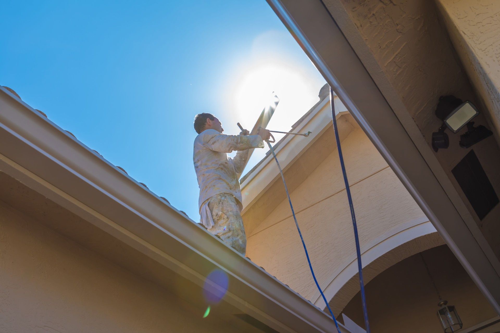 Series:House painter standing on roof spray painting trim